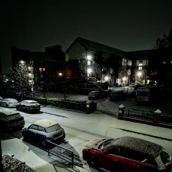 A nighttime photo of a street covered in snow.